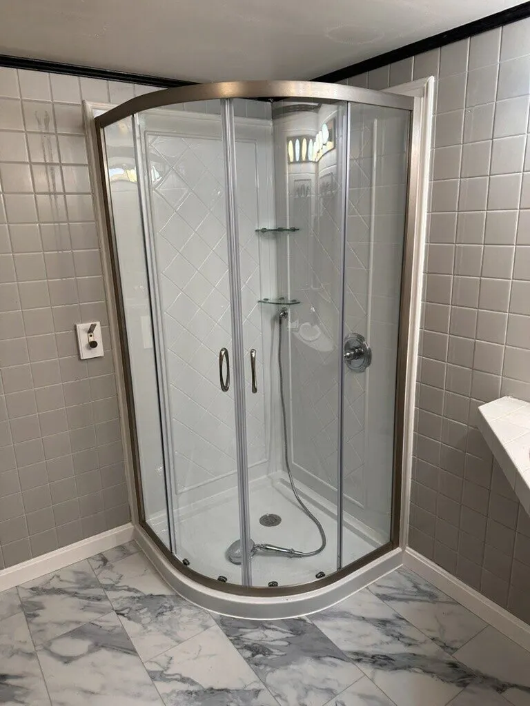 Rounded corner shower enclosure over a marble-look tile floor
