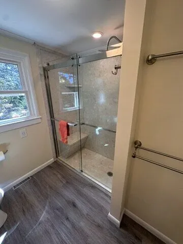 Glass-door shower with grab bars in a remodelled bathroom
