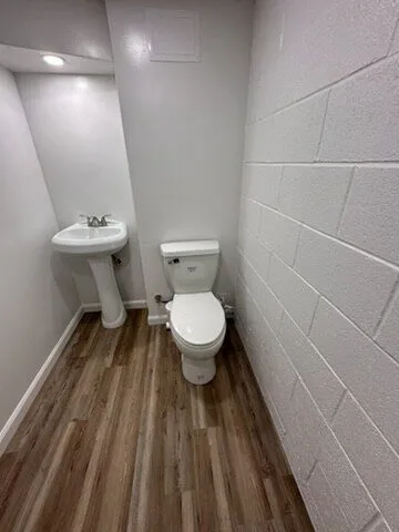 Small powder room with a pedestal sink, toilet and wood-look floor
