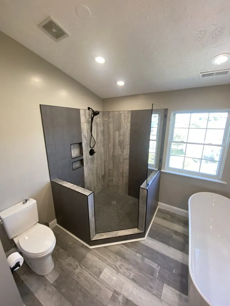 Tiled walk-in shower with a toilet and freestanding tub in a remodelled bathroom