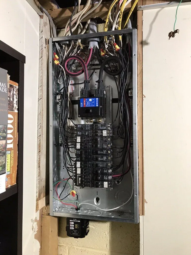 Open breaker panel with neatly dressed wiring set into a wall