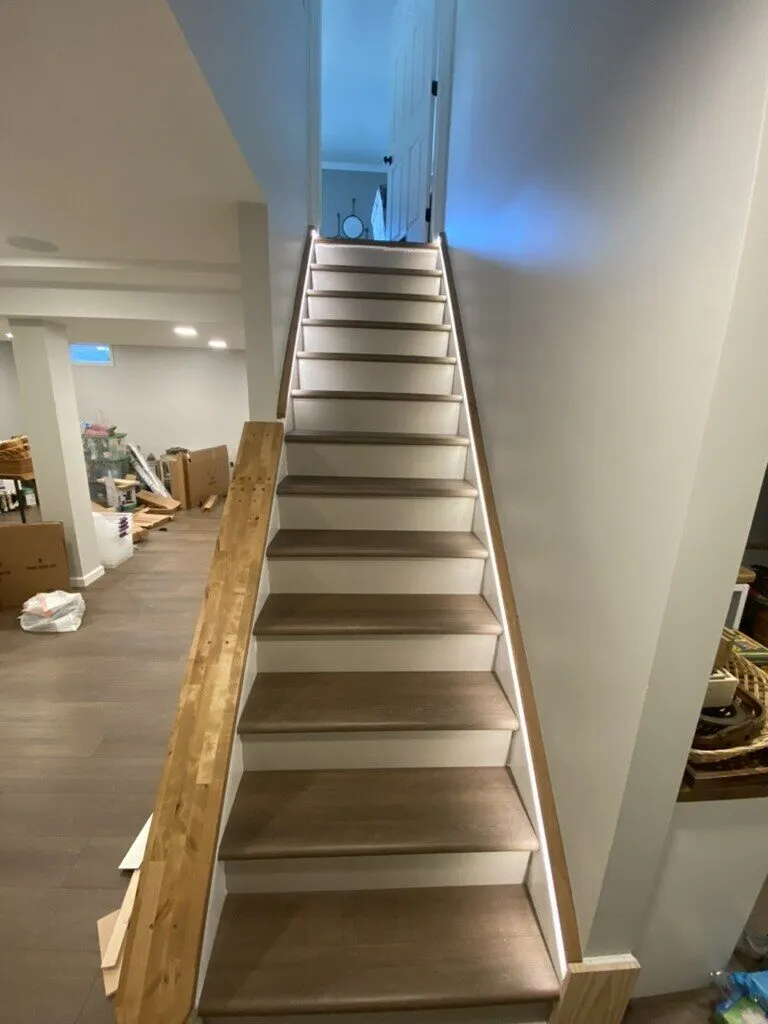 Finished basement staircase with new treads and a wood handrail