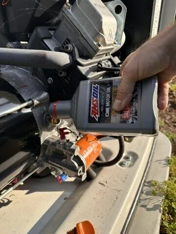 Technician pouring synthetic oil into a standby generator engine