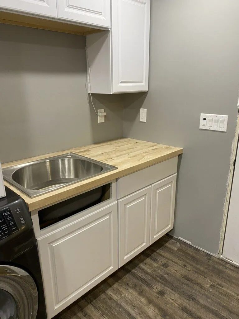 Utility sink set in a white base cabinet with a butcher-block top