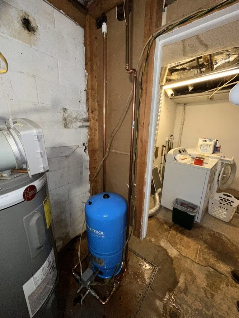 Well pressure tank and water heater in a basement utility area