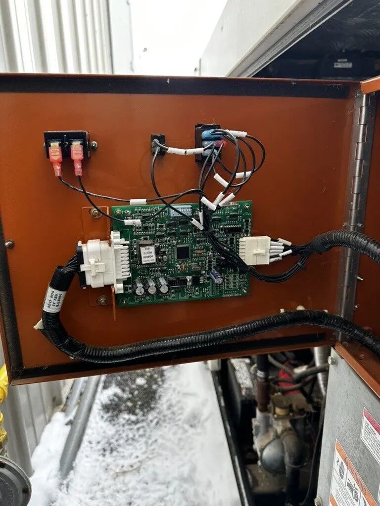Generator control panel opened to reach the circuit board on a snowy day