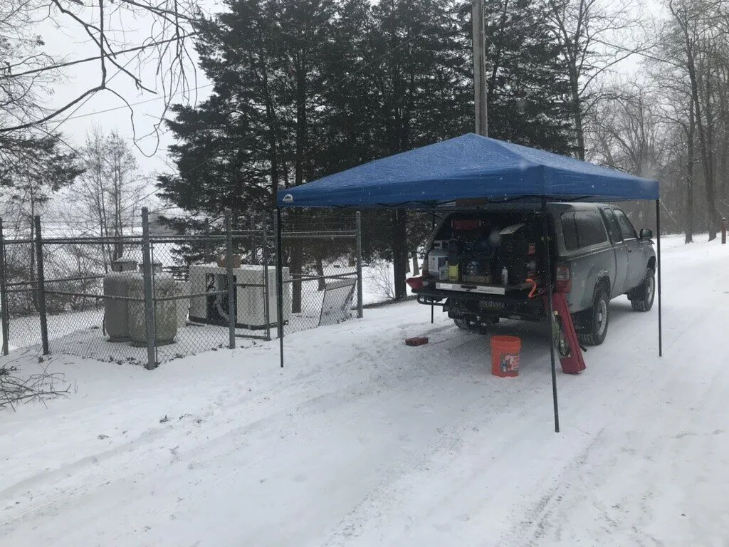 Service truck and pop-up canopy beside a generator in the snow